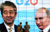 ournalists walk past a screen in the media center showing Russian President Vladimir Putin (right) and Japanese Prime Minister Shinzo Abe during the G20 summit on September 5, 2013 in Saint Petersburg.