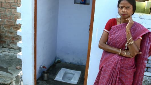 A woman stands next to her newly installed toilet in Agra, India.