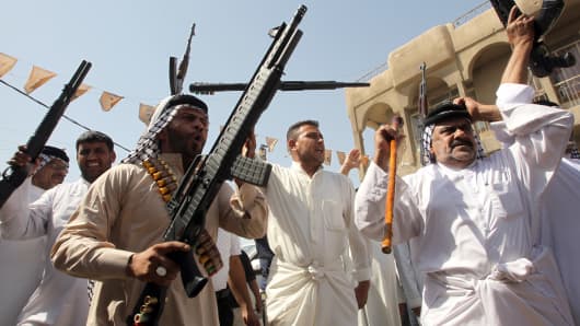 Iraqi tribes men carry their weapons as they gather, volunteering to fight along side the Iraqi security forces against Jihadist militants.