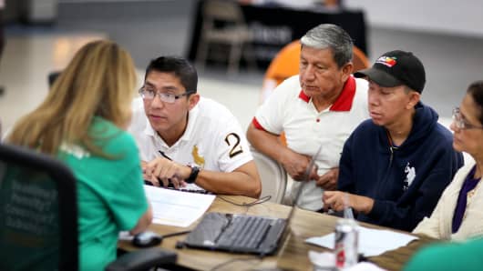 People sit with an insurance agent from Sunshine Life and Health Advisors as they try to purchase health insurance under the Affordable Care Act at the Mall of the Americas in March 2014 in Miami.