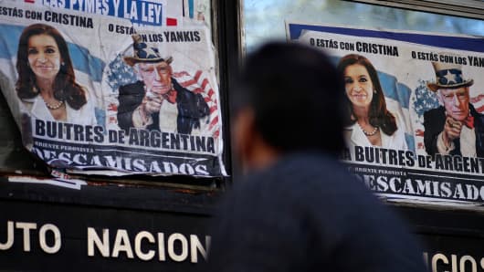 A man walks past posters with pictures of Argentina's President Cristina Fernandez de Kirchner and U.S. District Court for the Southern District of New York Judge Thomas Griesa, depicted as Uncle Sam, near the Argentine Congress in Buenos Aires, September 10, 2014.