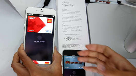 A worker demonstrates Apple Pay in a mobile kiosk sponsored by Visa and Wells Fargo to demonstrate the new Apple Pay mobile payment system, October 20, 2014 in San Francisco.