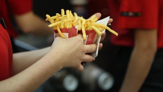 An employee collects two portions of french fries for a customer inside a Burger King fast food restaurant.