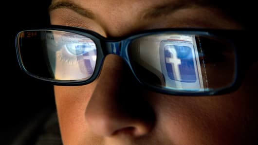 The Facebook logo is reflected in the eyeglasses of a user in San Francisco.