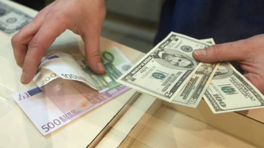 A clerk handles dollars and euros at a money exchange office in Paris.