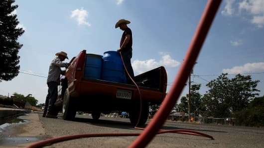 Residents fills buckets with non-potable water from a tank set up in front of the Doyle Colony Fire Station on April 23, 2015, in Porterville, California. Private wells here have gone dry.