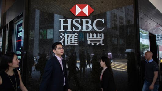 Pedestrians walk past a signage for HSBC Holdings Plc displayed outside a bank branch in the Central district of Hong Kong, China