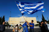A protester waves a Greek flag in front of the parliament building during a rally in Athens, Greece, June 22, 2015.