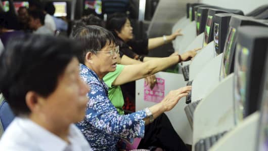Investors look at computer screens showing stock information at a brokerage house in Qingdao, Shandong province, China.