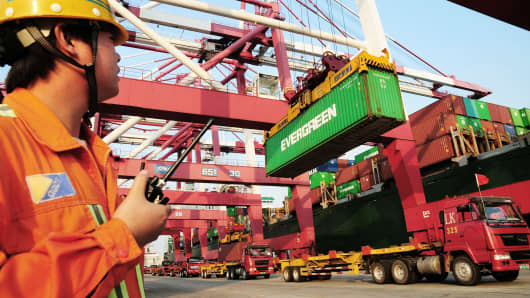 A worker monitors the loading of containers onto a ship at the harbor in Qingdao, China.