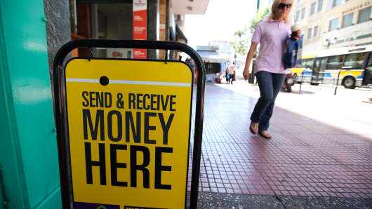 A pedestrian passes an advertising board outside a Western Union money transfer store in Athens, Greece.