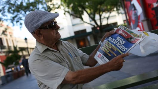 Tomas Colon reads a newspaper with a Spanish headline that reads, 'more sacrifices,' a day after the speech Puerto Rican Governor Alejandro Garcia Padilla gave regarding the government's $72 billion debt on June 30, 2015, in San Juan, Puerto Rico.