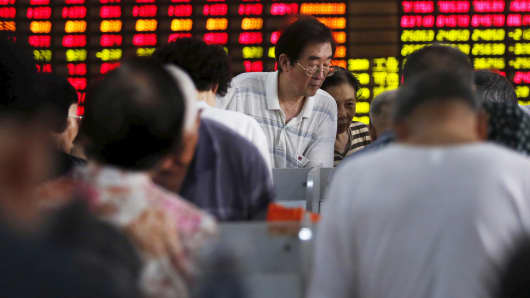 Investors look at an electronic board showing stock information at a brokerage house in Shanghai.