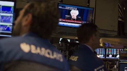 Traders work as Janet Yellen, chair of the U.S. Federal Reserve, is seen speaking on a television screen on the floor of the New York Stock Exchange (NYSE) in New York, U.S., on Thursday, Sept. 17, 2015.