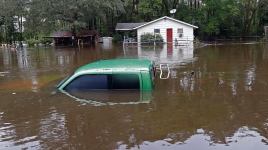 A vehicle and a home are swamped with floodwater from nearby Black Creek in Florence, South Carolina, Monday, Oct. 5, 2015.
