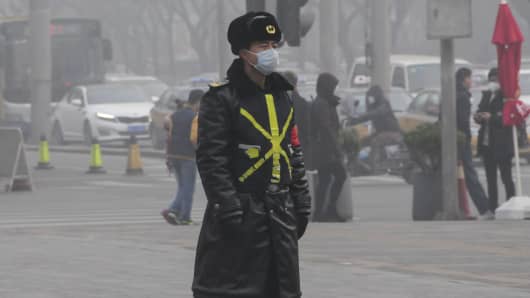 A Chinese man walking on a street wears a mask amid heavy smog in Beijing, China on December 25, 2015. Hazardous smog blanketing China's north-east has sparked more red alerts, with authorities advising residents in 10 cities to stay indoors.