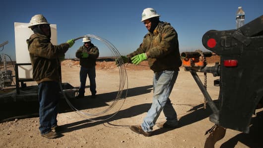 Employees of Stewarts Inc., an oil field service company, work on a chemical drum at a drilling site in the Permian Basin oil field on Jan. 20, 2016, in the oil town of Andrews, Texas.
