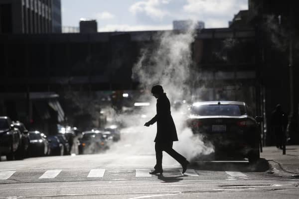 A woman walks through steam rising from the ground along Fort Street in Detroit, Michigan.