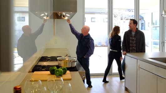 Prospective buyers with their real estate agent survey the kitchen of a new home in Denver.