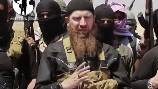 This image made from undated video posted during the weekend of June 28, 2014 on a social media account frequently used for communications by the Islamic State of Iraq and the Levant (ISIL), which has been verified and is consistent with other AP reporting, shows Omar al-Shishani standing next to the group's spokesman among a group of fighters as they declare the elimination of the border between Iraq and Syria.