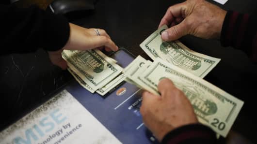 A shopper counts U.S. dollar banknotes at a checkout counter