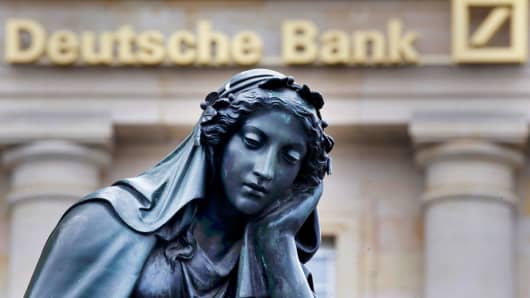 A statue is seen next to the logo of Germany's Deutsche Bank in Frankfurt, Germany.