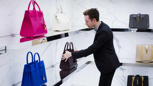 A retail worker adjusts a display of handbags in a Nordstrom store.