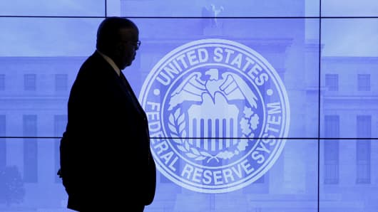 A security guard walks in front of an image of the Federal Reserve in Washington.