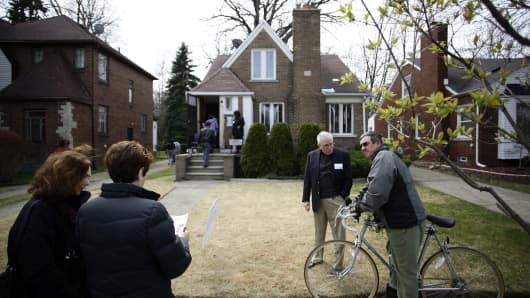 People stand outside of a home for sale in the East English Village neighborhood of Detroit.