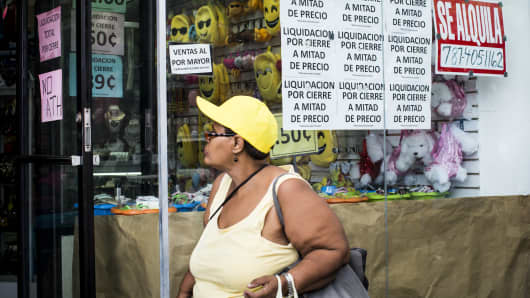 A pedestrian walks past a store that is under liquidation in the Rio Piedras neighborhood in San Juan, Puerto Rico