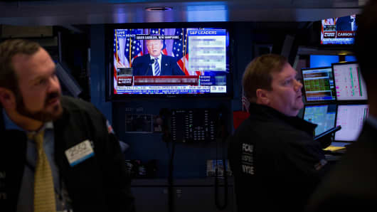 Traders at the New York Stock Exchange watch Donald Trump speaking on TV.