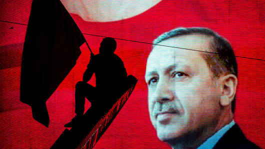 A supporter of Turkish President Recep Tayyip Erdogan waves a flag against an electronic billboard during a rally in Kizilay Square on July 18, 2016 in Ankara, Turkey.