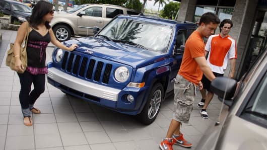 Customers look at a Jeep vehicle for sale on the sales lot of a Chrysler Jeep Dodge dealership in Miami.