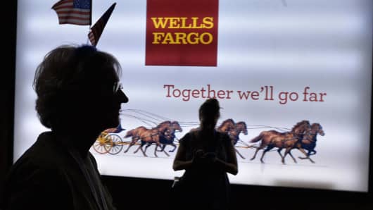 A woman passes a Wells Fargo sign.