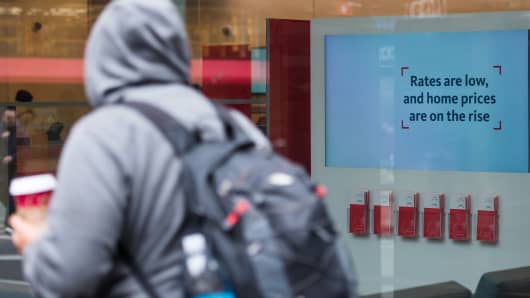 A pedestrian walks past a sign that reads 'Rates are low and home prices are on the rise' inside a Santander bank branch in New York.
