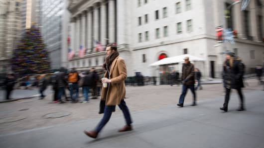 Pedestrians walk along Wall Street in front of the New York Stock Exchange, Dec. 21, 2016.