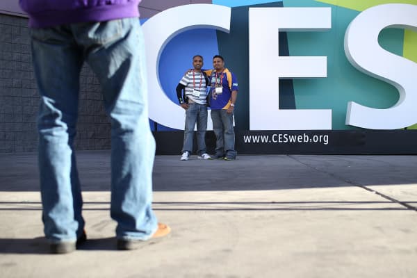 Attendees take their photo in front of a sign as they arrive at the International CES at the Las Vegas Convention Center.