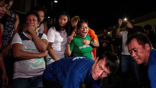 This picture taken on January 5, 2017, shows relatives crying as coroners carry away the body of an alleged drug dealer killed during a drug buy bust operation in Manila.