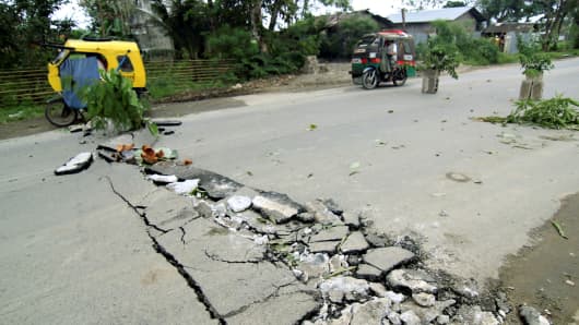 Véhicules passent des fissures sur une route qui est apparue le long de la route nationale à la ville de Rizal après un tremblement de terre a frappé la ville de Surigao, le sud des Philippines Février 11, 2017.