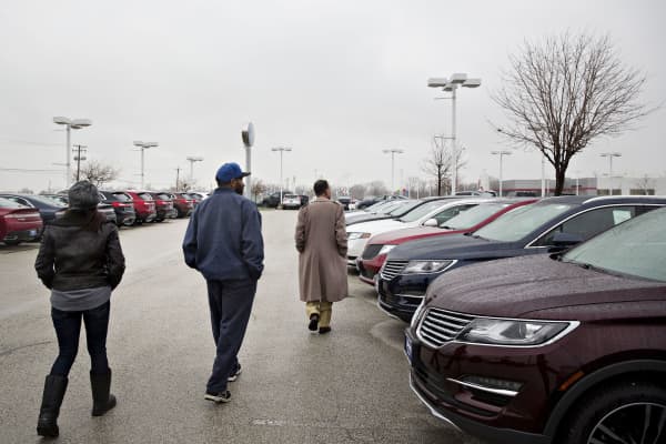 A couple walks with a salesman, right, while shopping for a new vehicle at the Sutton Ford Lincoln car dealership in Matteson, Illinois.