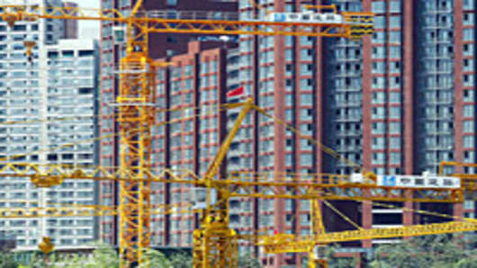 Cranes stand on a construction site in front of newly completed apartment buildings in Beijing.