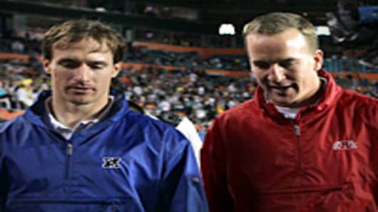 Drew Brees of the New Orleans Saints and Peyton Manning of the Indianapolis Colts walk on the field during 2010 AFC-NFC Pro Bowl at Sun Life Stadium.