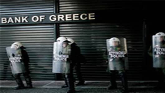 Riot police line up outside a closed branch of the National Bank of Greece during a 24-hour general strike.