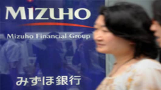 Women walk past the logo of Japan's second-largest bank Mizuho Financial Group in Tokyo.
