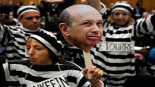 Demonstrators from Code Pink for Peace hold photographs of Lloyd Blankfein, chairman and CEO of The Goldman Sachs Group, and demand he be jailed with other executives before a hearing of the Senate Homeland Security and Governmental Affairs Investigations Subcommittee on Capitol Hill.