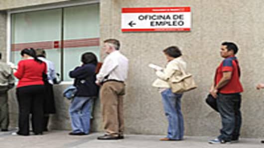 People wait in line at a government employment office in the center of Madrid.