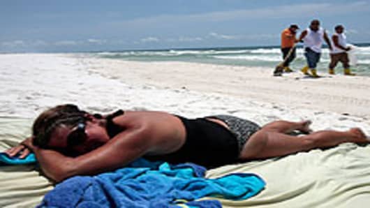 Woman lies on the beach as workers clean up tar balls on the Gulf Islands National Seashore, Pensacola Beach, Florida.
