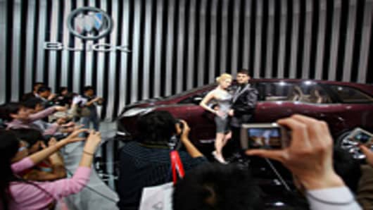 Two models stand beside Buick Business concept car during the Beijing Auto Show.