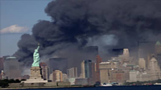 The view from Jersey City, NJ of The Statue of Liberty and the burning remains of the World Trade Center after two airliners crashed into the buildings on Tuesday morning, September 11, 2001.