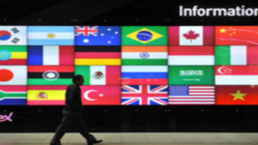 A man walks in front of a screen showing flags of the participating nations for the upcoming G20 Summit at its venue in Seoul on November 4, 2010.